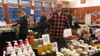 a man standing in front of soap products in an indoor market.